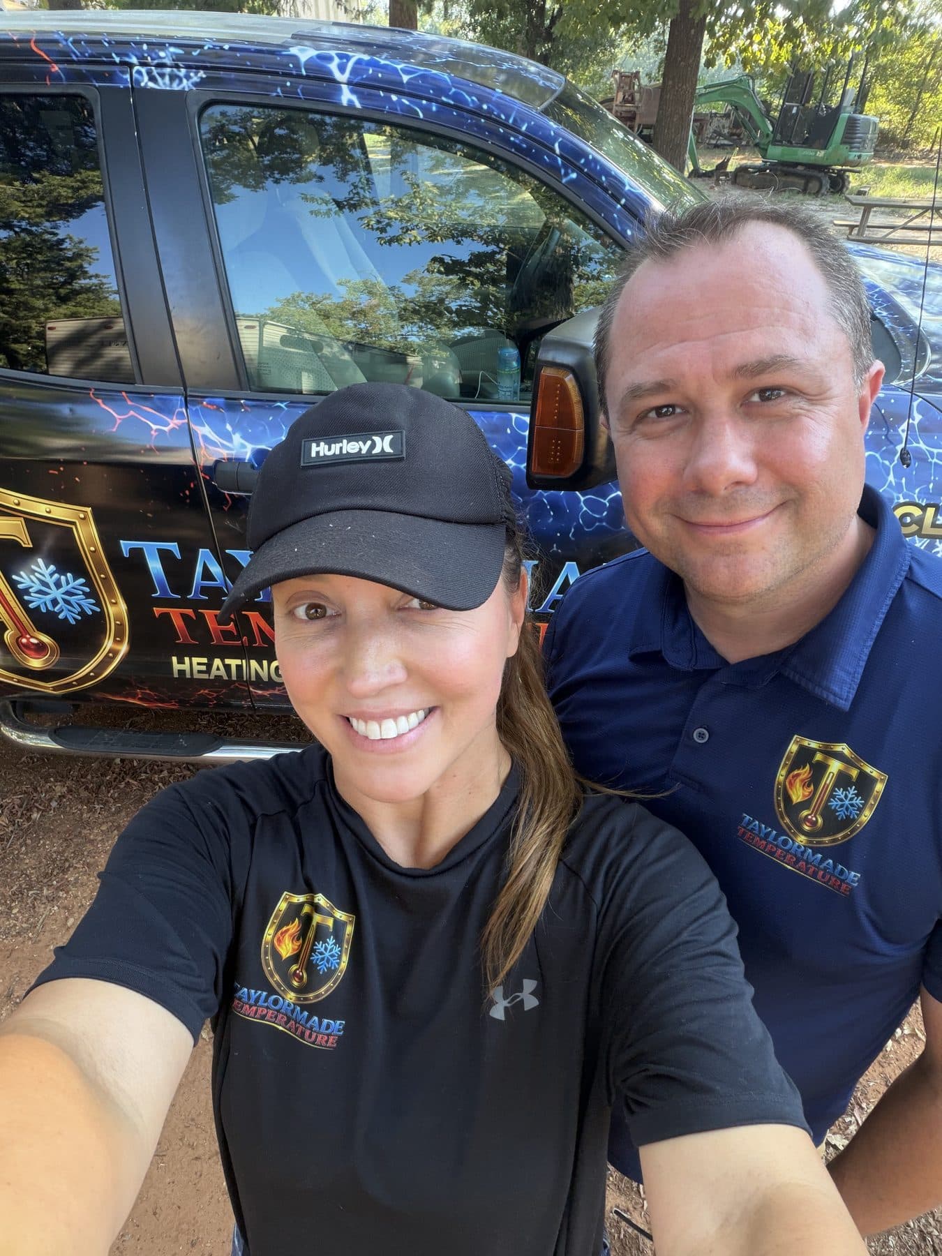 Chad and Melissa Taylor in branded TaylorMade Temperature shirts, standing in front of their service truck